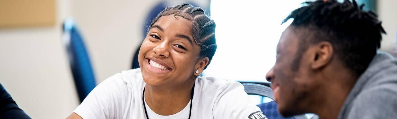 A girl smiling while sitting at a table.